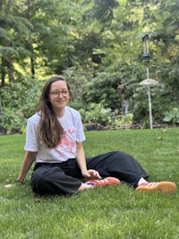 a young woman sitting on the grass in a garden
